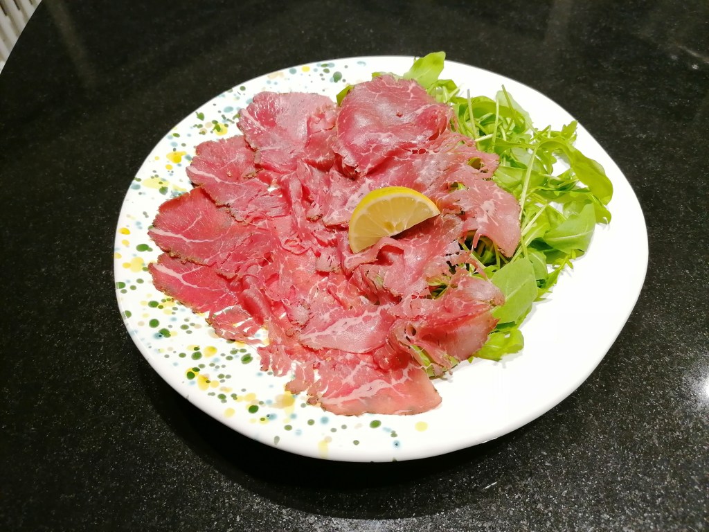 Angus marinato su letto di rucola servito su un piatto di ceramica artistica toscana Le Lentiggini di Lifestyle Verde